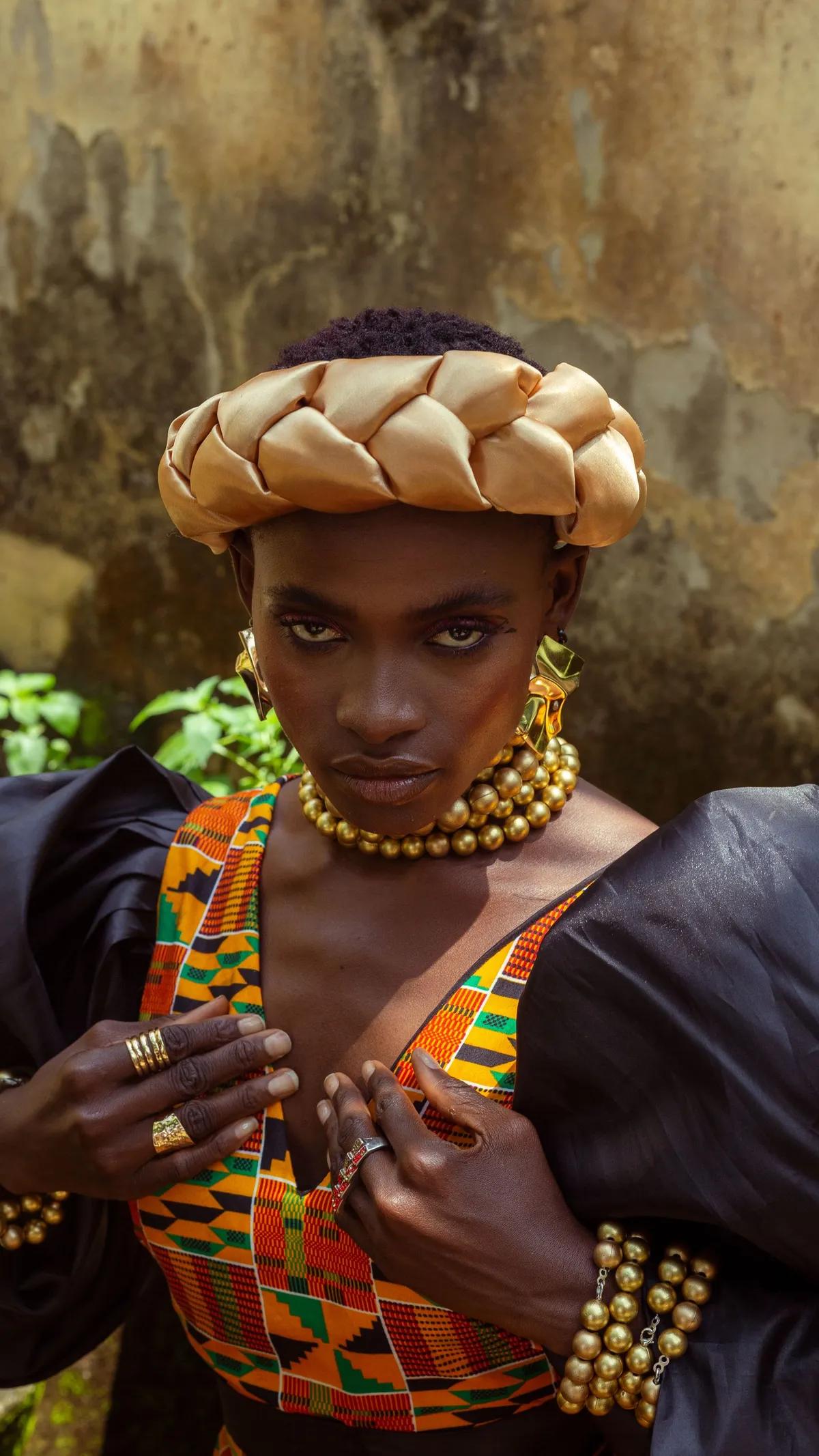Femme en kente, couronne tressée et bijoux dorés